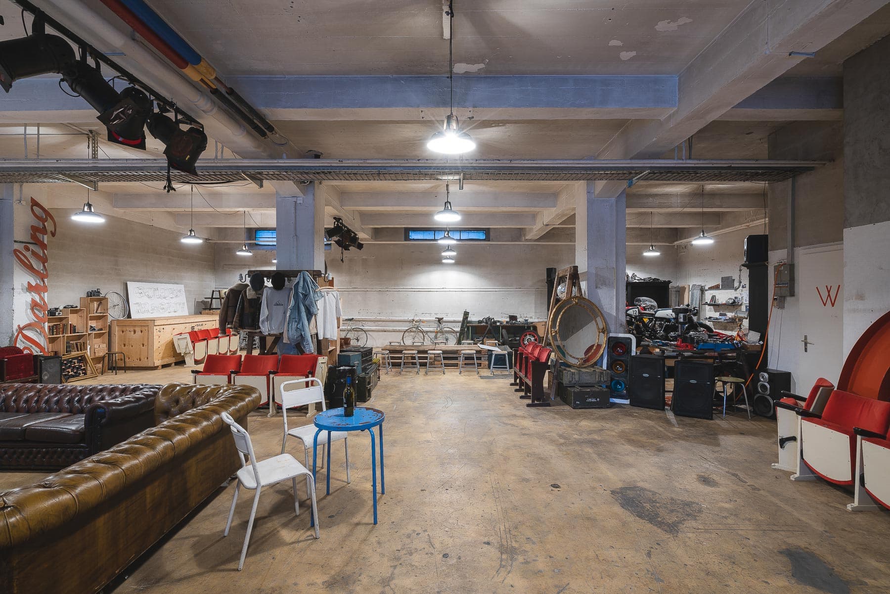 Intérieur d'entrepôt de 240m² mettant en valeur la lumière naturelle à travers de grandes fenêtres, plafond industriel exposé et espace ouvert polyvalent parfait pour événements privés, expositions et célébrations à Lausanne